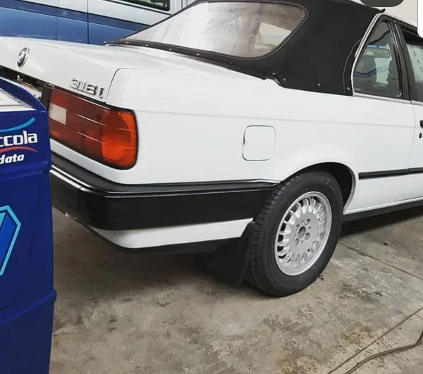 A white BMW E30 convertible in the Iceberg workshop