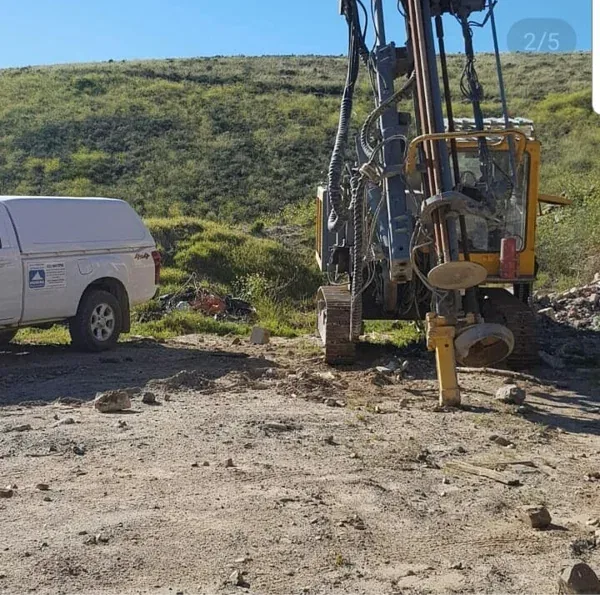 An Iceberg bakkie beside a tracked drill rig on a hillside