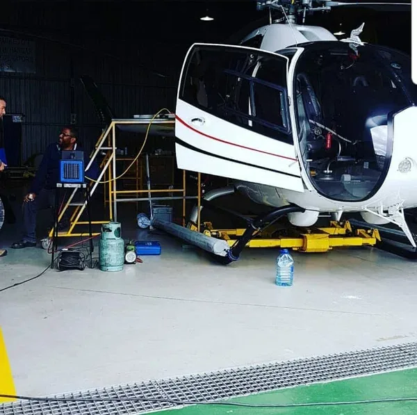 A helicopter in a hangar with aircon equipment alongside it