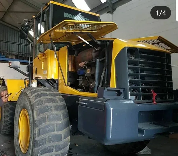 A Komatsu front-end loader with its engine bay open in the workshop