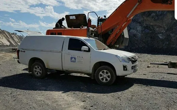 An Iceberg bakkie parked beside an excavator at a quarry