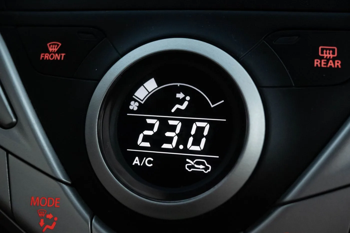 A car climate control dial set to 23 degrees with the A/C switched on