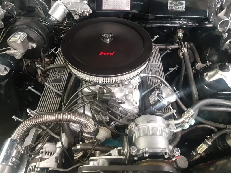 A classic Ford V8 engine bay with the aircon system fitted, chrome and immaculate