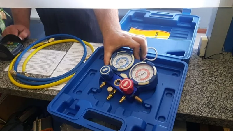 An aircon manifold gauge set being lifted out of its case in the Iceberg workshop