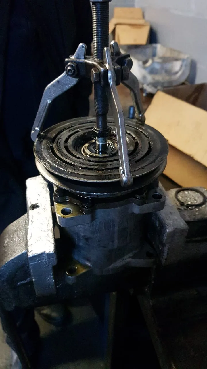 An aircon compressor clamped in a vice being stripped and reconditioned