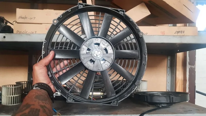 A condenser fan held up in front of the parts shelves at Iceberg